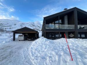 a house with a pile of snow in front of it at Moderne hytte på Fjellsætra, Ski in/Out, Familievennlig in Sykkylven