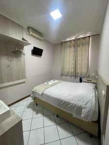 a small bedroom with a bed and a window at Hotel Villa Souza Ltda in Santa Cruz do Sul
