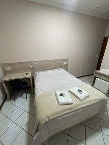 a bedroom with a bed with two towels on it at Hotel Villa Souza Ltda in Santa Cruz do Sul