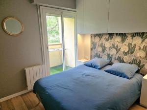 a bedroom with a bed with blue sheets and a window at Joli appartement avec balcon in Cabourg