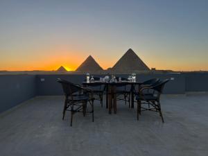 Pyramids Hotel في القاهرة: طاولة وكراسي مع الاهرامات في الخلفية
