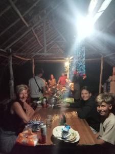 grupa ludzi siedzących przy drewnianym stole w obiekcie Ransiwor Homestay w mieście Kri