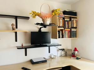 a desk with a computer on a wall with books at Apartament Cornelia in Buzău