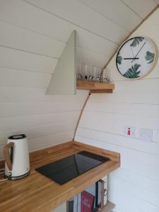 a small kitchen in a tiny house with a clock on the wall at Handa pod in scottish highlands. in Scourie