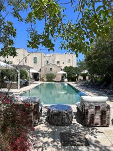 una piscina con 2 sillas y una mesa en Palazzo Siena - Home & More, en Minervino di Lecce