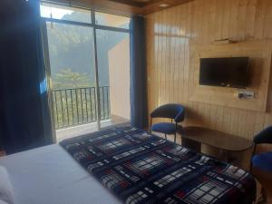 a bedroom with a bed and a tv and a window at Aagaman Woods in Shimla