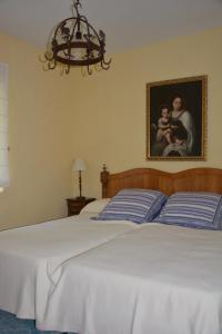 een slaapkamer met een bed met een schilderij en een kroonluchter bij Los Naranjos in Trujillo