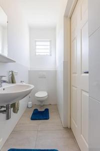 Cocobana Resort two-bedroom apartment ground floor في فيليمستاد: حمام أبيض مع حوض ومرحاض