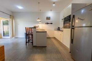 a kitchen with a refrigerator and a table with chairs at Cocobana Resort two-bedroom apartment ground floor in Willemstad