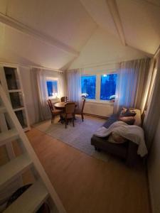 sala de estar con cama, mesa y ventanas en Litet strandnära hus på Adelsö, en Adelsö