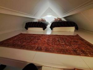 2 Betten in einem kleinen Zimmer mit einem Teppich in der Unterkunft Litet strandnära hus på Adelsö in Adelsö