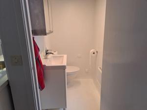 a white bathroom with a sink and a toilet at Litet strandnära hus på Adelsö in Adelsö