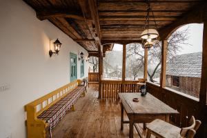 a porch with a wooden table and a wooden bench at La bujda lu mosu in Borşa