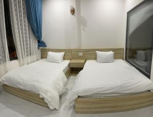 Thiên Thanh Hotel في دالات: سريرين في غرفة ذات أغطية بيضاء