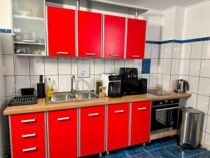 a kitchen with red cabinets and a sink at Valea Albă View - SELF CHECK-IN in Buşteni
