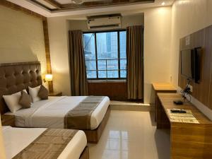 ムンバイにあるHotel BKC Mannatのベッド2台とテレビが備わるホテルルームです。