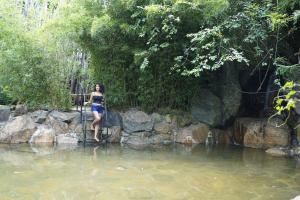 une femme debout sur une clôture dans une rivière dans l'établissement The Glenrock, à Belihuloya