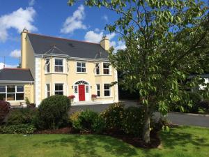 una gran casa amarilla con puerta roja en Barr's Guest Accommodation, en Moville