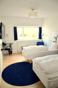 two beds in a room with a desk and a blue rug at Hotel DGI-Huset Herning in Herning