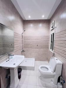 a bathroom with a white toilet and a sink at بوابة الريادة in Ar Riḩāb