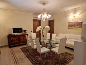 a dining room with a glass table and white chairs at Appartamento centrale elegante in Olbia