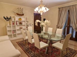 a dining room with a glass table and white chairs at Appartamento centrale elegante in Olbia