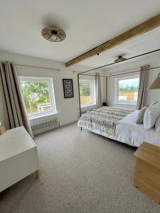 a bedroom with a large bed and two windows at The Pines, At Bull Bay in Amlwch
