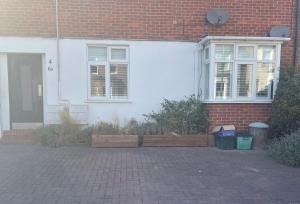 Elmers End的住宿－4 Birkbeck Road Beckenham BR3 4SN，前面有长凳的白色房子