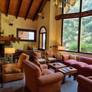 uma sala de estar com sofás, cadeiras e janelas em Altos Los Pioneros & Spa em Villa La Angostura
