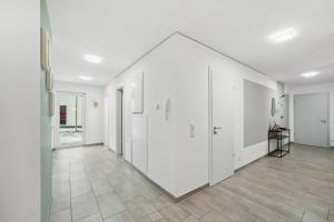 an empty hallway with white walls and tile floors at Sali Homes AM14 großes Apartment mit Terrasse im Zentrum in Bayreuth