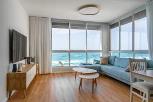 a living room with a blue couch and a table at O&O Group - Amazing Seaview 3 BR Apartment in Bat Yam