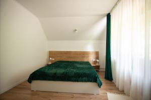 a bedroom with a bed with a green blanket at GREEN ROSIA in Lazuri