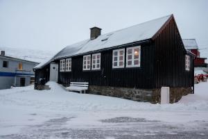 Live in the history of Faroe Island في Syðrugøta: منزل أسود مع مقعد في الثلج