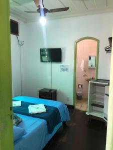 a bedroom with a blue bed and a flat screen tv at Pousada Coco Verde in Paraty