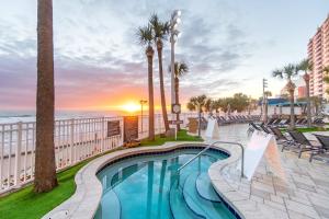 een zwembad met palmbomen en de oceaan bij 16th Floor 1 BR Resort Condo Direct Oceanfront Wyndham Ocean Walk Resort Daytona Beach 1606 in Daytona Beach