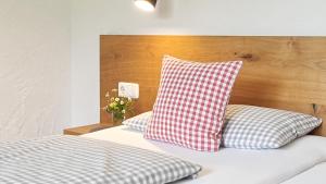 a bed with two red and white pillows on it at Goldvogel Apartments in Fischen