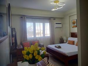 a bedroom with a bed and a vase of yellow flowers at Ehime Suites One Regis Bacolod in Bacolod
