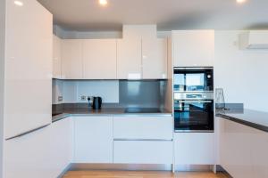 una cocina con armarios blancos y electrodomésticos de acero inoxidable en FORBES Suite1206-Hosted by Sweetstay, en Gibraltar