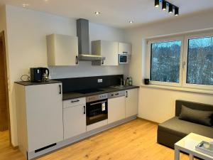 a kitchen with white cabinets and a couch in a room at Haus Sonnenwinkl in Kössen