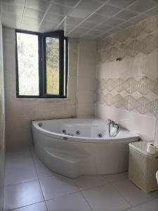 Holistic Balance : حمام أبيض مع حوض استحمام ونافذة