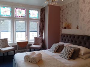 a bedroom with two beds and two chairs and windows at Durham House in Beer