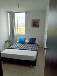 1 dormitorio con 1 cama con 2 almohadas azules en Apto con Piscina 3km parque del cafe, en Pueblo Tapado
