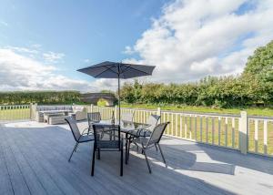 a table and chairs with an umbrella on a deck at Winston Farm Lodges 