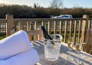 Una botella de champán sentada en una mesa con copas en Yare View Holiday Cottages en Brundall