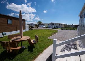 a wooden table and bench with a surfboard next to a house at Looe Coastal Retreat in Looe