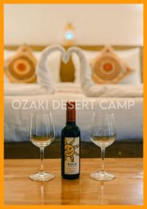 Una botella de vino y dos copas en una mesa. en Ozaki Desert Camp, en Jaisalmer
