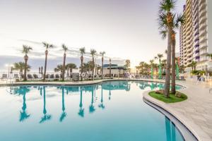 une grande piscine bordée de palmiers et un bâtiment dans l'établissement 17th Floor 1 BR Resort Condo Direct Oceanfront Wyndham Ocean Walk Resort Daytona Beach 1706, à Daytona Beach