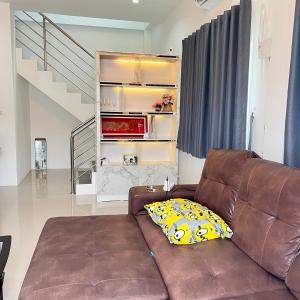 un soggiorno con divano marrone e cuscino giallo di บ้านเดี่ยว 4 ห้องนอน 3 ห้องน้ำ a Ban Noi Pho Kham