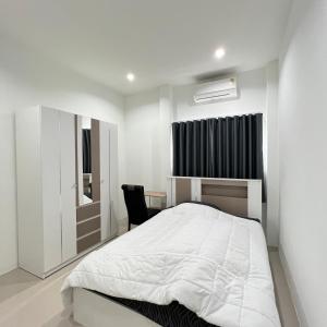 1 dormitorio blanco con 1 cama y 1 silla en บ้านเดี่ยว 4 ห้องนอน 3 ห้องน้ำ en Ban Noi Pho Kham