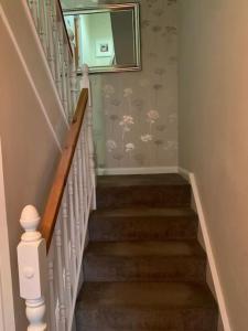 a staircase with a mirror on the wall with flowers on it at Central 3 Bedroom Townhouse in Wick